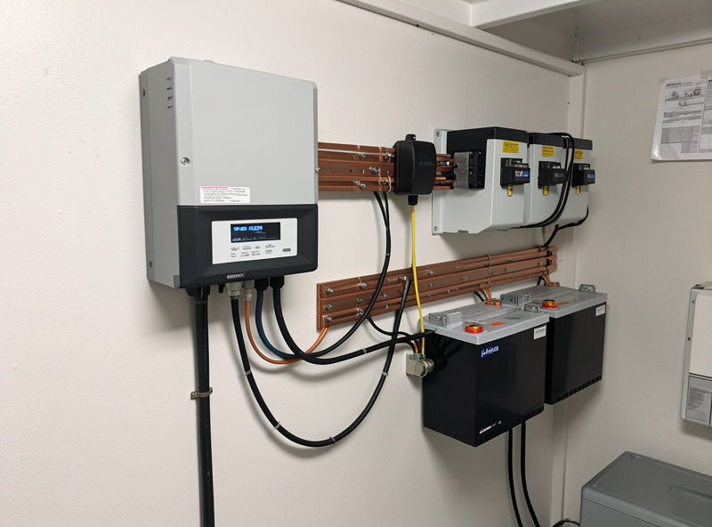Hybrid inverter and LiFePO4 battery bank wired with busbars and a Class-T fuse in an off-grid power system