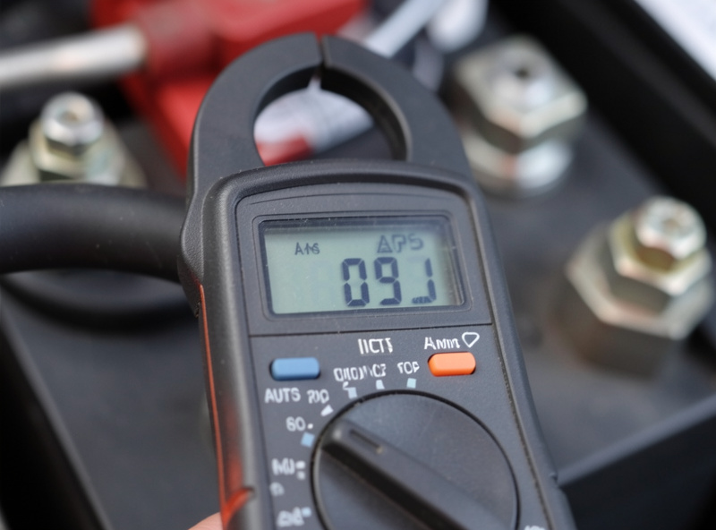 Close-up of a digital clamp meter reading amps on a heavy battery cable